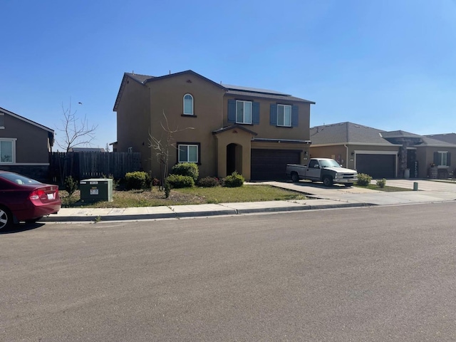 traditional-style house featuring stucco siding, driveway, an attached garage, and fence