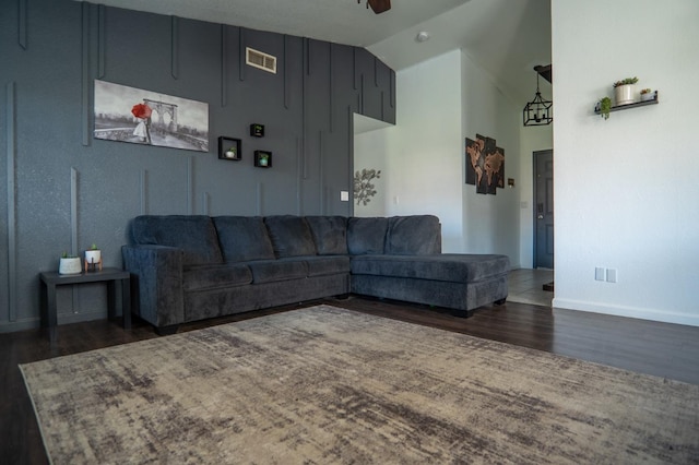 living room featuring lofted ceiling, ceiling fan, visible vents, baseboards, and dark wood finished floors