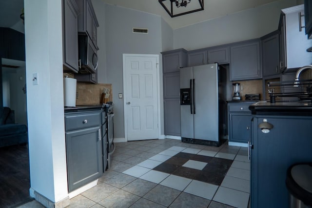 kitchen with stainless steel appliances, dark countertops, visible vents, and gray cabinetry