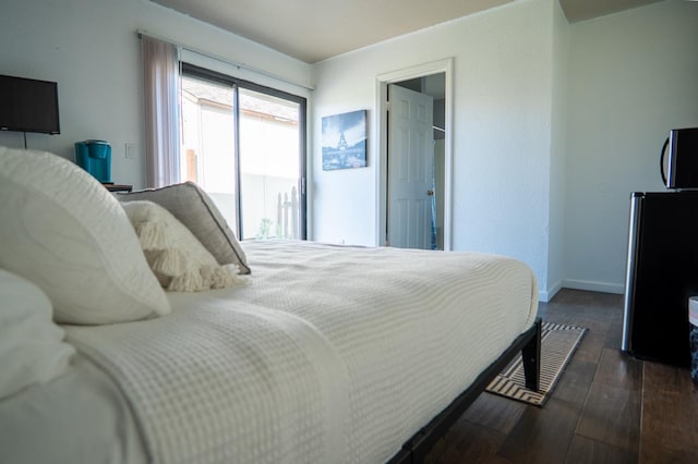 bedroom featuring baseboards, dark wood finished floors, and freestanding refrigerator