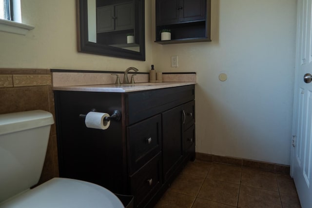 bathroom with toilet, vanity, baseboards, and tile patterned floors