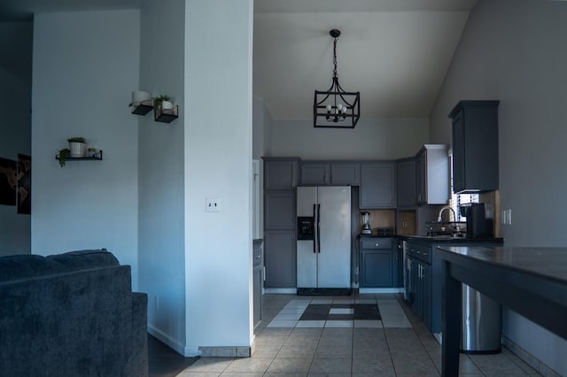 kitchen featuring dark countertops, gray cabinets, an inviting chandelier, stainless steel fridge, and baseboards