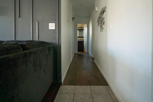 hallway with baseboards and tile patterned floors