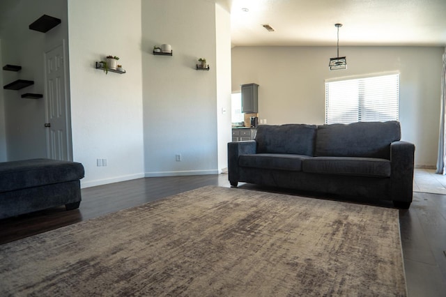 living room with lofted ceiling, baseboards, visible vents, and dark wood finished floors