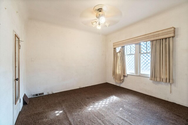 carpeted empty room with visible vents and ceiling fan