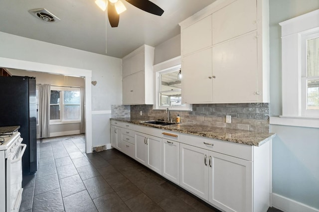 kitchen featuring a wealth of natural light, visible vents, decorative backsplash, a sink, and gas range gas stove