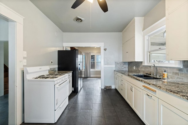 kitchen featuring decorative backsplash, white gas stove, a sink, and light stone countertops