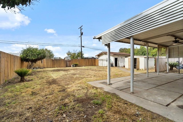 view of yard featuring an outbuilding, ceiling fan, a patio area, and a fenced backyard