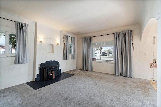 unfurnished living room featuring carpet floors and a wood stove