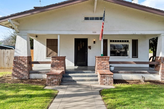 view of front of house featuring fence, a porch, and stucco siding