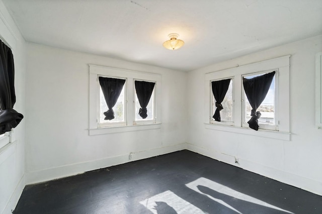 spare room featuring finished concrete flooring and baseboards