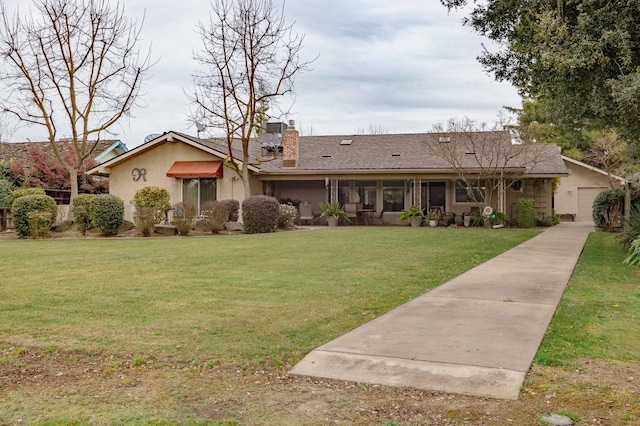 view of front of house featuring a garage, a chimney, a front yard, and stucco siding