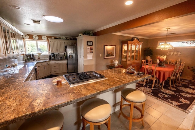 kitchen with stainless steel appliances, visible vents, a sink, a peninsula, and a kitchen bar