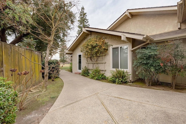 view of home's exterior with fence and stucco siding