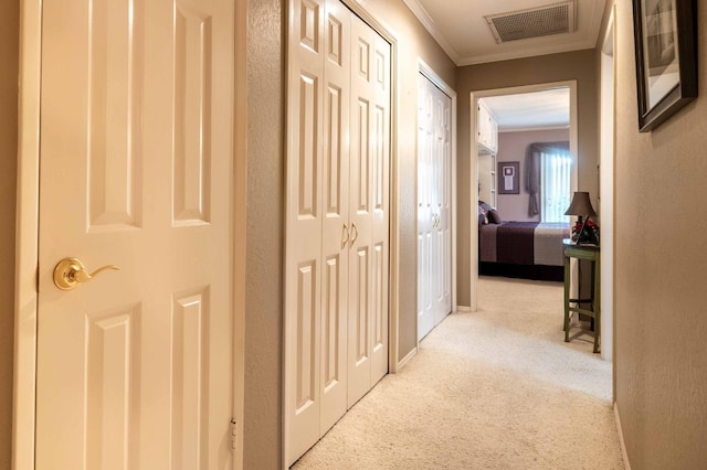 hall featuring baseboards, carpet, visible vents, and crown molding