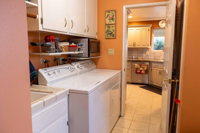 clothes washing area featuring cabinet space, light tile patterned flooring, and washing machine and clothes dryer