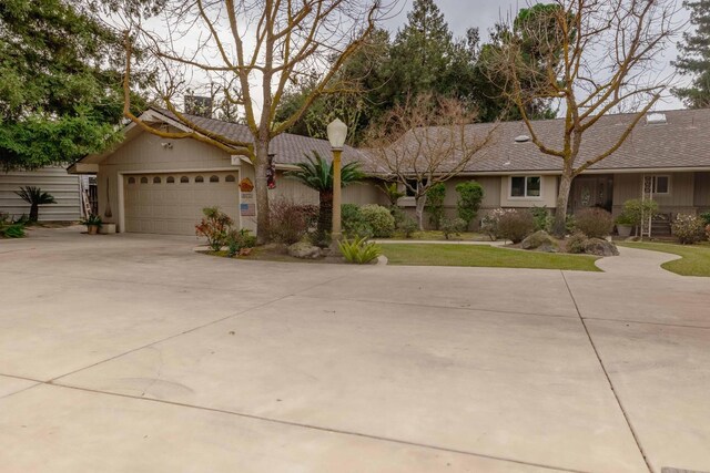 ranch-style house with concrete driveway, an attached garage, and stucco siding