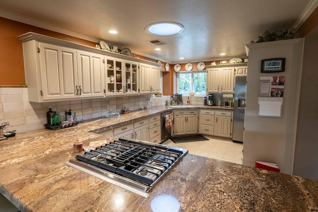 kitchen featuring crown molding, stainless steel appliances, visible vents, decorative backsplash, and a sink