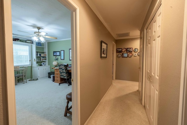 corridor featuring visible vents, baseboards, light colored carpet, and crown molding