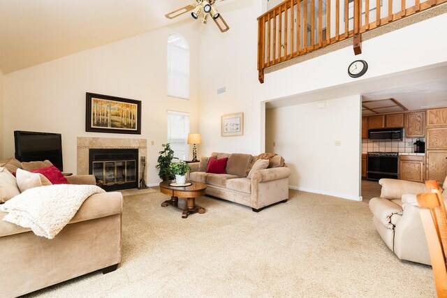 carpeted living area with baseboards, visible vents, ceiling fan, a premium fireplace, and high vaulted ceiling