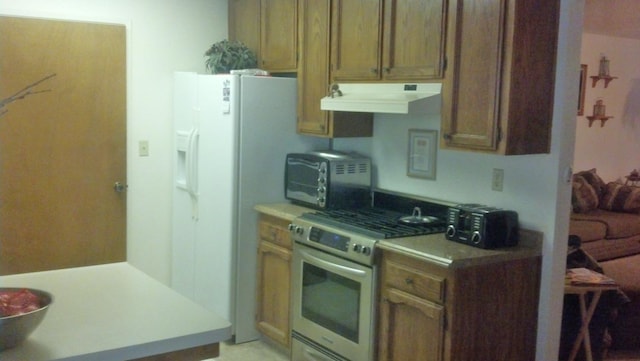 kitchen with stainless steel gas range, light countertops, a toaster, and under cabinet range hood