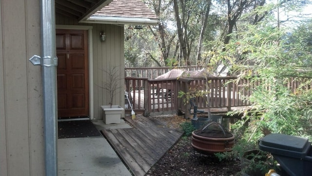 doorway to property featuring roof with shingles and a deck