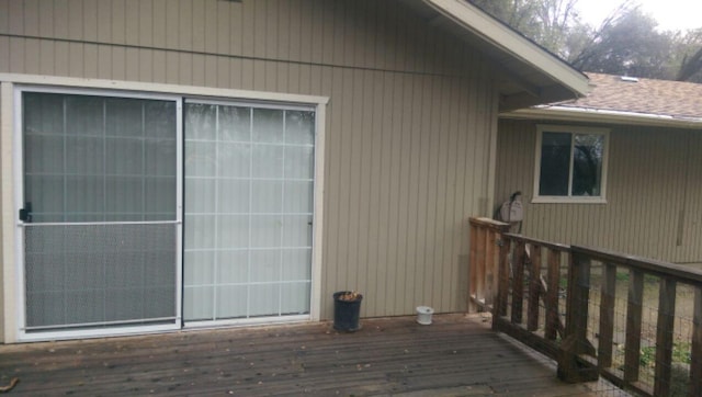 view of side of property with a shingled roof and a wooden deck