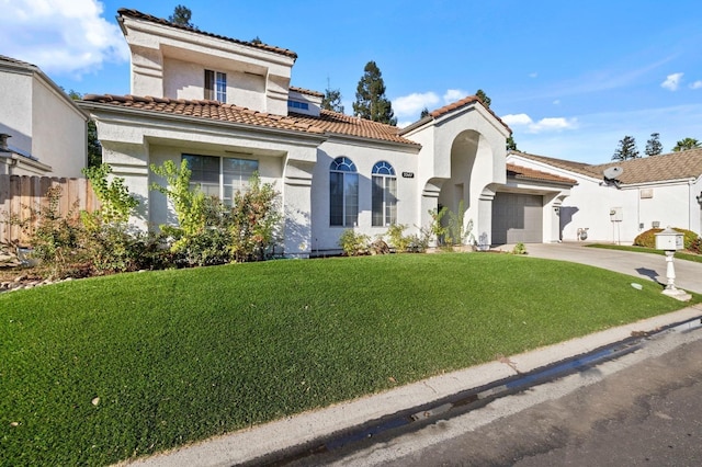 mediterranean / spanish-style home featuring an attached garage, driveway, a tiled roof, stucco siding, and a front lawn