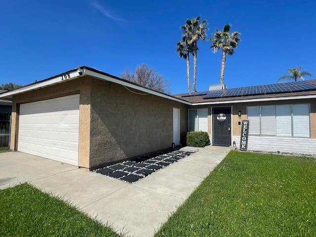 single story home featuring an attached garage, solar panels, driveway, stucco siding, and a front yard