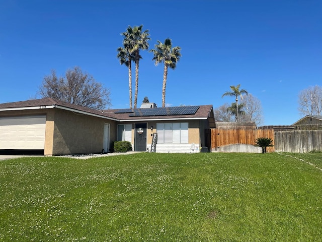 view of front of property with a garage, solar panels, a front yard, and stucco siding