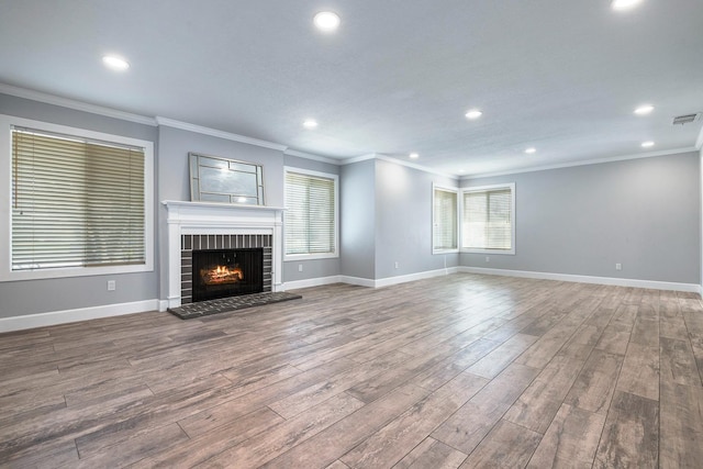 unfurnished living room with a brick fireplace, wood finished floors, visible vents, and baseboards