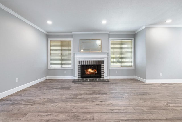 unfurnished living room featuring a brick fireplace, baseboards, and wood finished floors