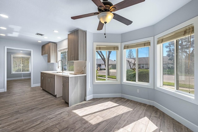 kitchen featuring light countertops, visible vents, a sink, wood finished floors, and baseboards