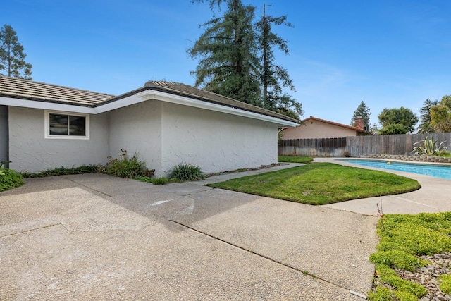 view of side of home featuring a patio, a fenced backyard, and stucco siding