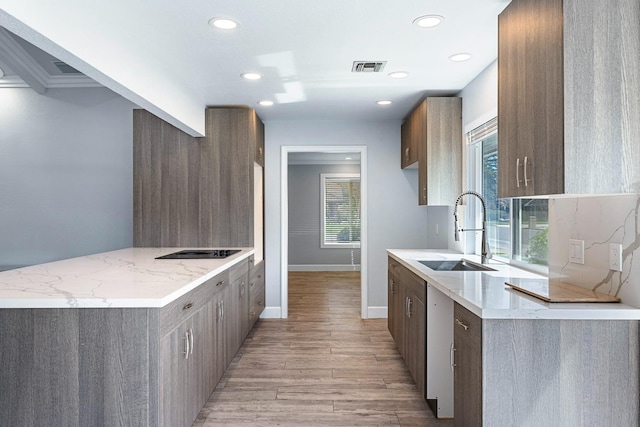 kitchen with recessed lighting, a peninsula, a sink, visible vents, and light wood-type flooring