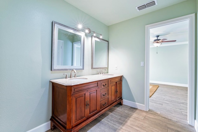 bathroom featuring baseboards, visible vents, a sink, and wood finished floors