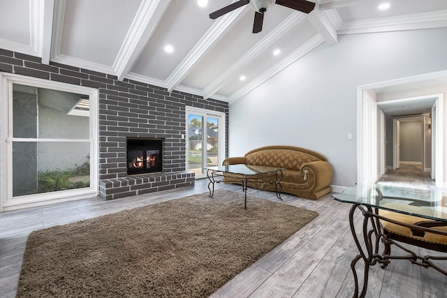 living room with crown molding, a fireplace, beamed ceiling, and wood finished floors