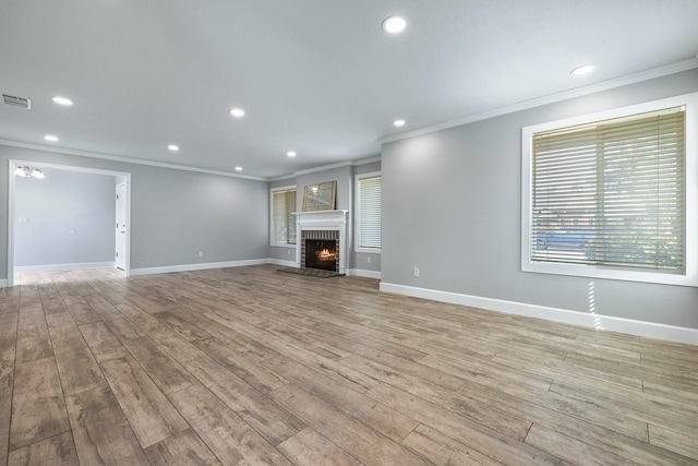 unfurnished living room featuring ornamental molding, a brick fireplace, and wood finished floors