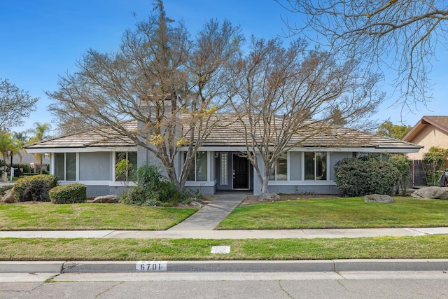 ranch-style home with a front yard and stucco siding