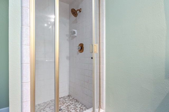 bathroom featuring a textured wall and a shower stall