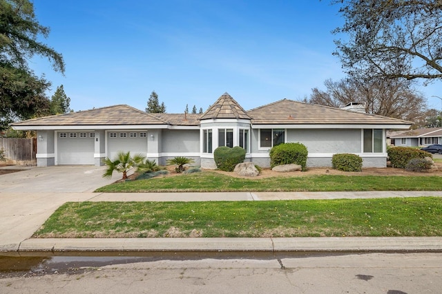 view of front of property featuring an attached garage, fence, concrete driveway, stucco siding, and a front lawn