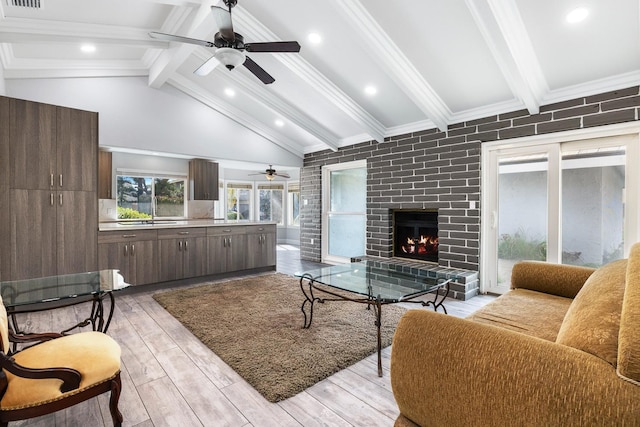 living room with light wood finished floors, crown molding, a fireplace, and beam ceiling