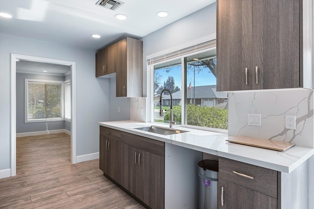 kitchen featuring light wood-type flooring, a healthy amount of sunlight, visible vents, and a sink