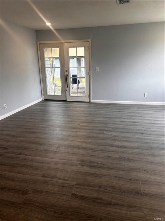 spare room featuring visible vents, baseboards, and dark wood-type flooring