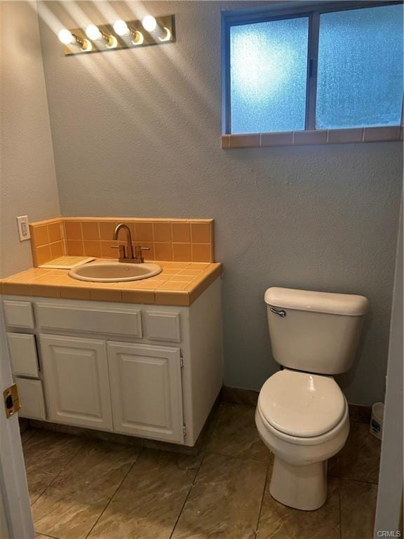 bathroom with tasteful backsplash, vanity, and toilet