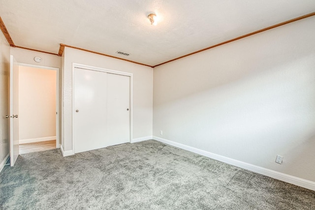 unfurnished bedroom with ornamental molding, carpet flooring, visible vents, and baseboards