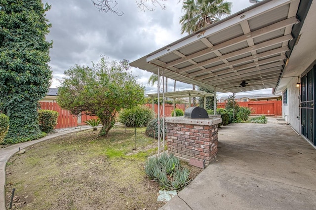 view of patio / terrace with exterior kitchen, a fenced backyard, and a ceiling fan