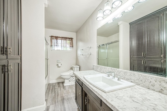 bathroom featuring baseboards, vanity, toilet, and wood finished floors