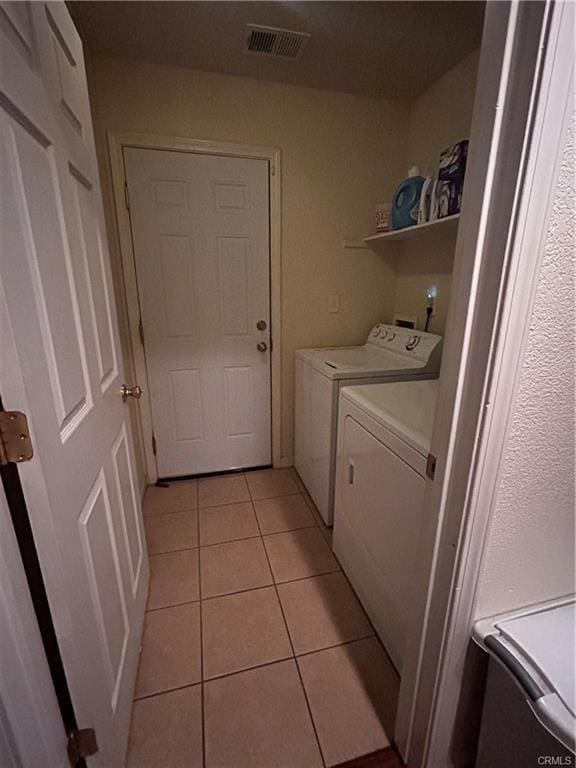 washroom with laundry area, light tile patterned floors, visible vents, and separate washer and dryer