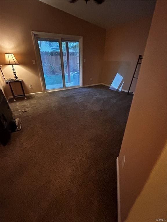 empty room with vaulted ceiling and dark colored carpet